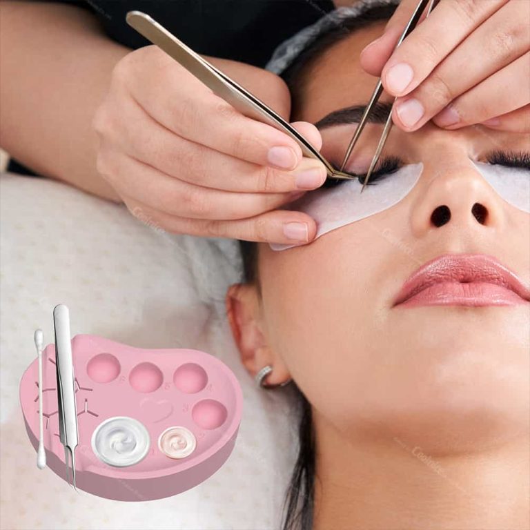 Pink silicone palette used during eyelash extension application with glue wells and tweezer slots.