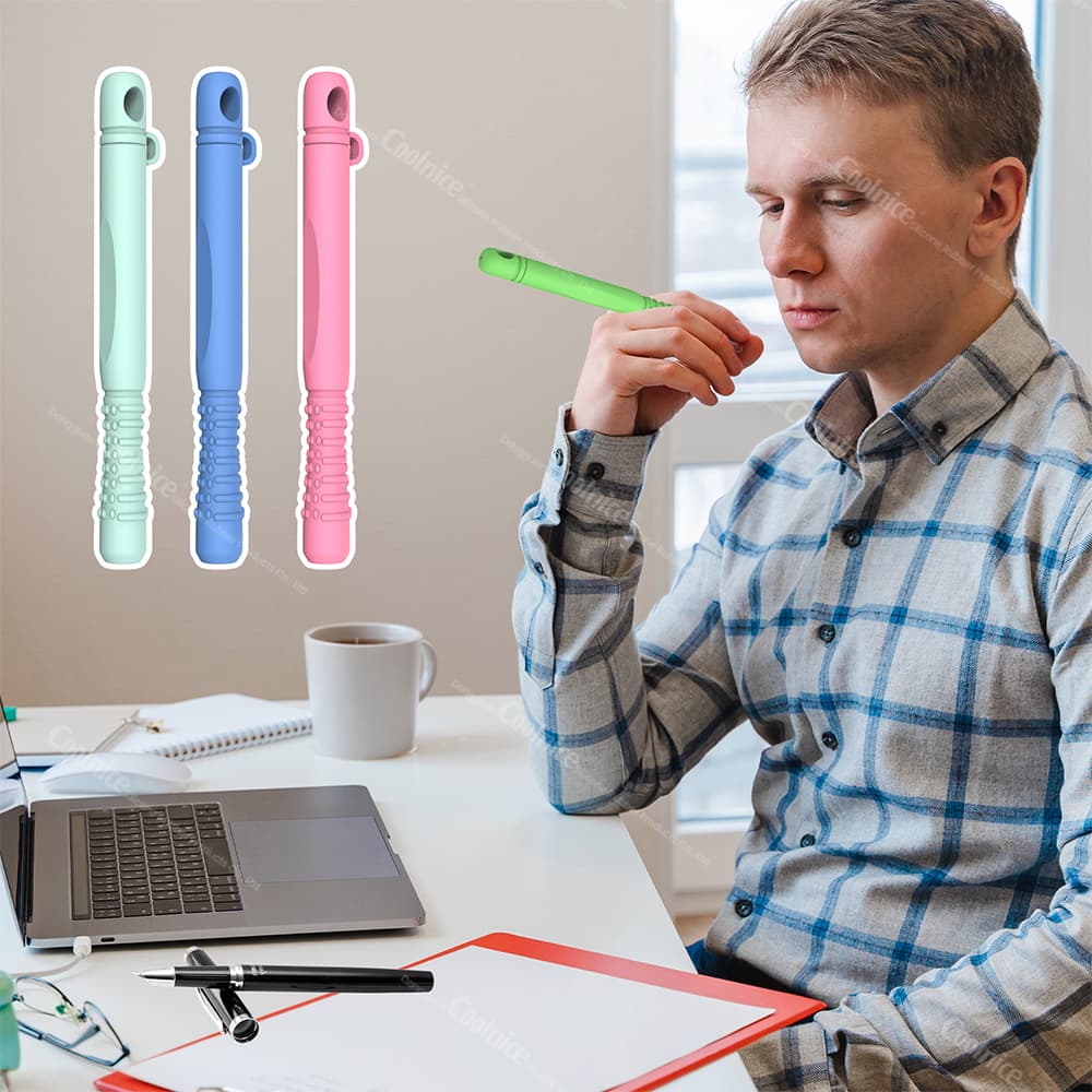 Person using a green silicone essential oil chewing stick for stress relief at their desk, with other color options (mint, blue, pink) shown in the background.