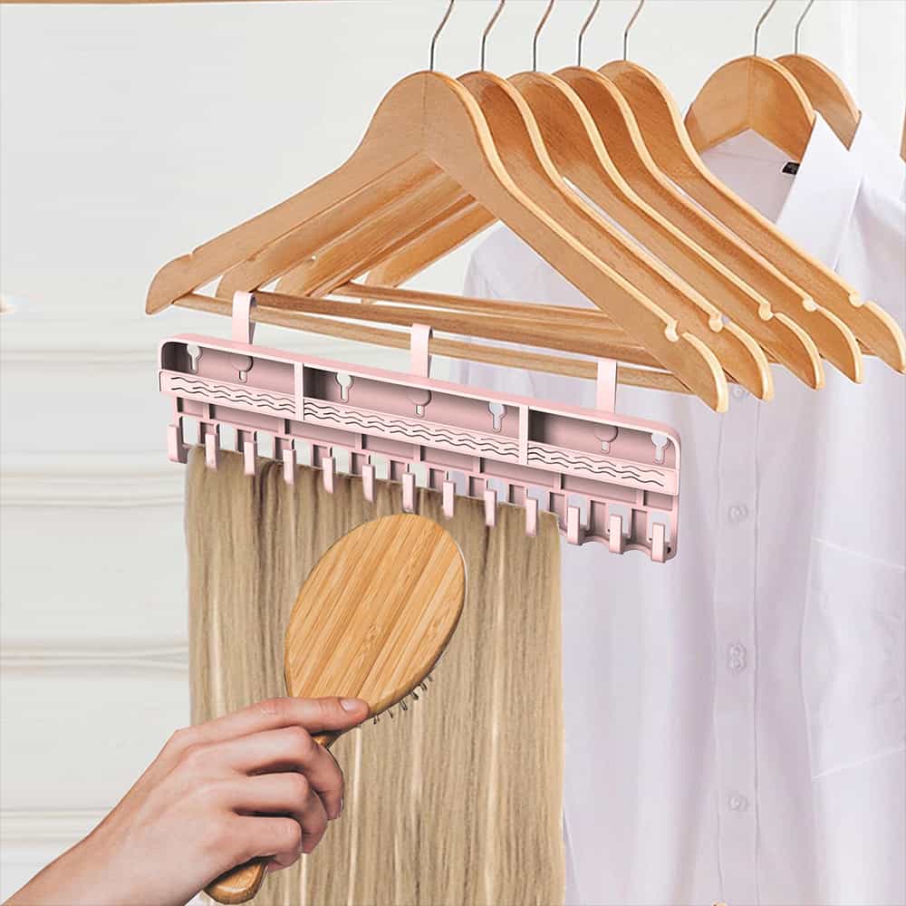 Wig storage rack hanging on wooden hangers with hairpiece being combed