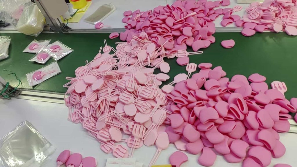 Pink silicone lip brush boxes being manufactured and packaged in factory