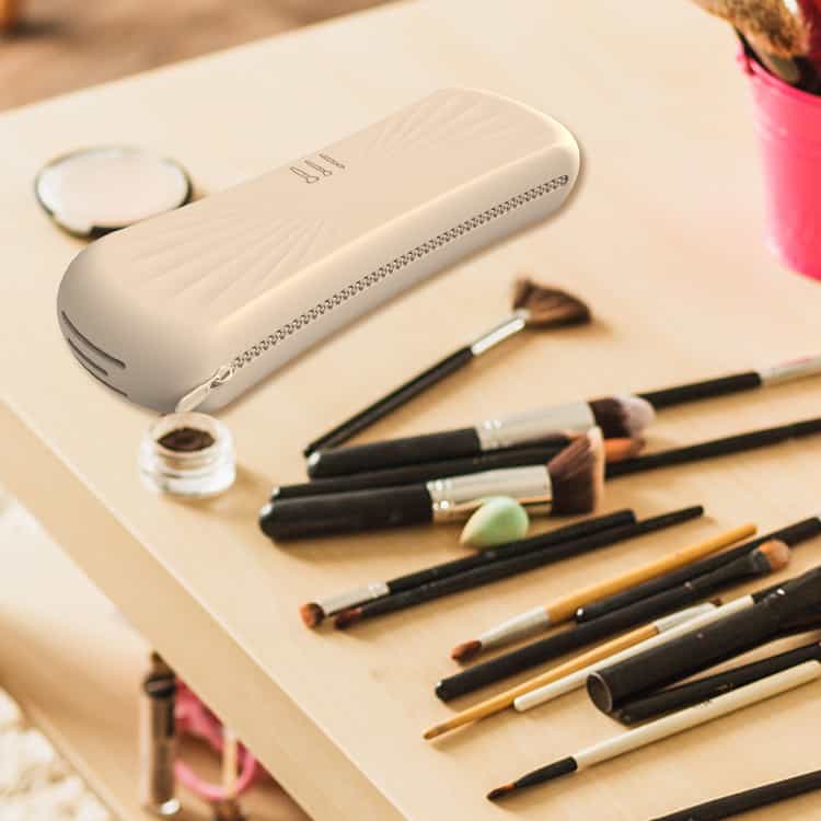Silicone brush holder placed on a makeup desk surrounded by brushes and cosmetics