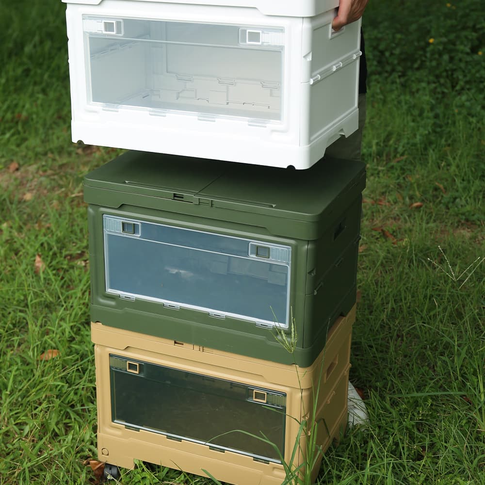 Stacked outdoor folding storage boxes in white, green, and khaki colors on grass