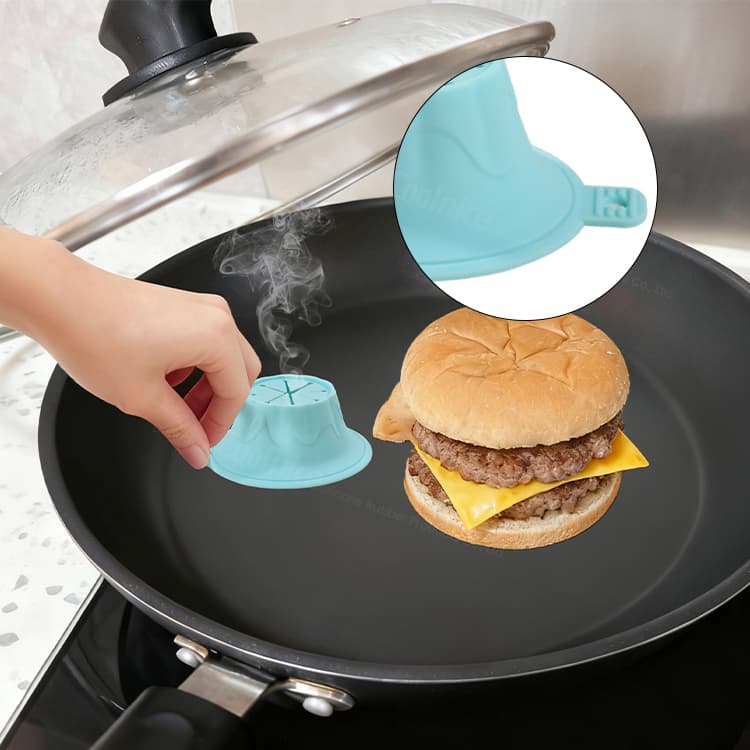 Hand lifting silicone burger steamer with rising steam on a frying pan