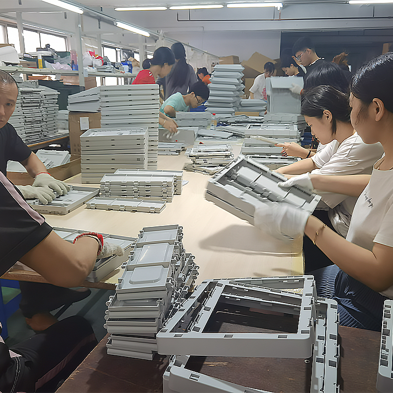 Factory workers assembling gray folding storage box panels